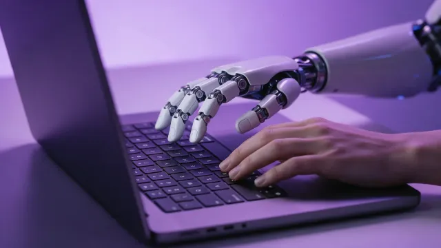 magnific__a-robot-hand-and-a-human-hand-typing-on-one-laptop__31890.webp